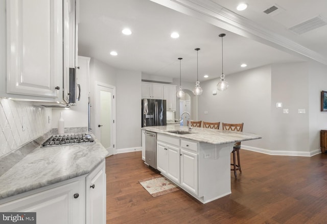 kitchen with sink, white cabinetry, stainless steel appliances, light stone countertops, and a kitchen island with sink