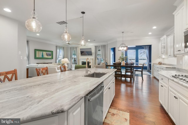 kitchen featuring sink, white cabinetry, stainless steel dishwasher, pendant lighting, and a kitchen island with sink