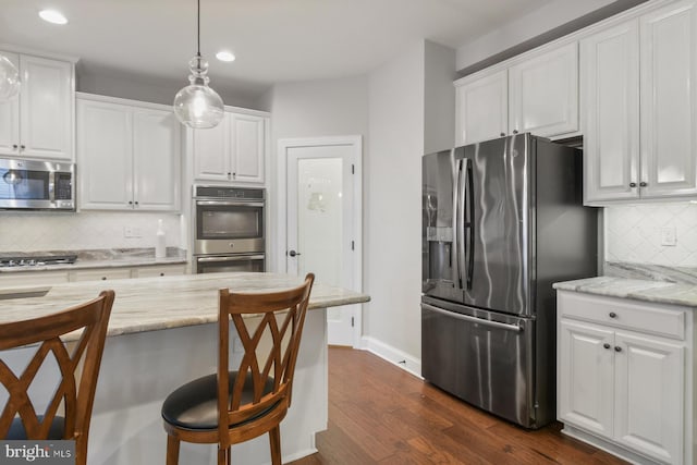 kitchen with white cabinetry, decorative light fixtures, a breakfast bar, and appliances with stainless steel finishes