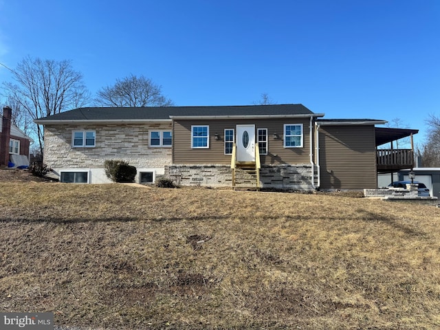 view of front facade with entry steps, stone siding, and a front lawn