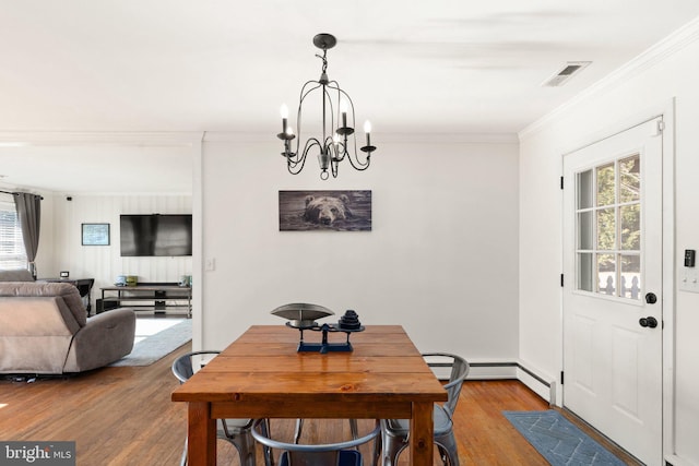 dining area featuring crown molding, a notable chandelier, and hardwood / wood-style flooring