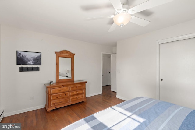 bedroom featuring a baseboard heating unit, hardwood / wood-style floors, ceiling fan, and a closet