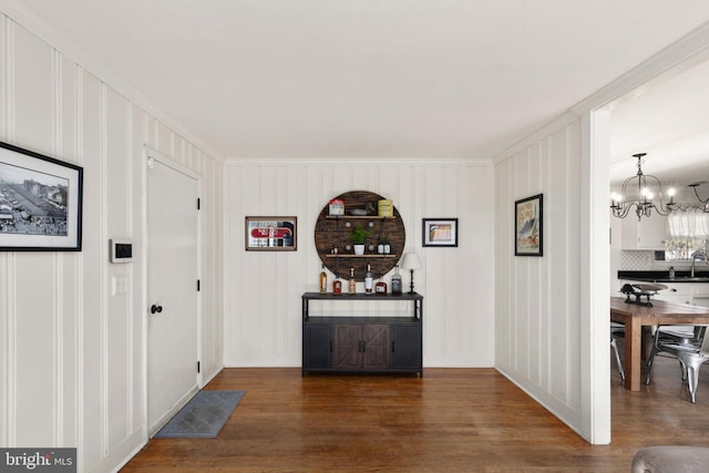 hallway with an inviting chandelier, sink, and dark hardwood / wood-style floors