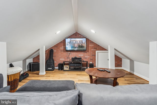 living area featuring brick wall, lofted ceiling with beams, baseboards, and wood finished floors