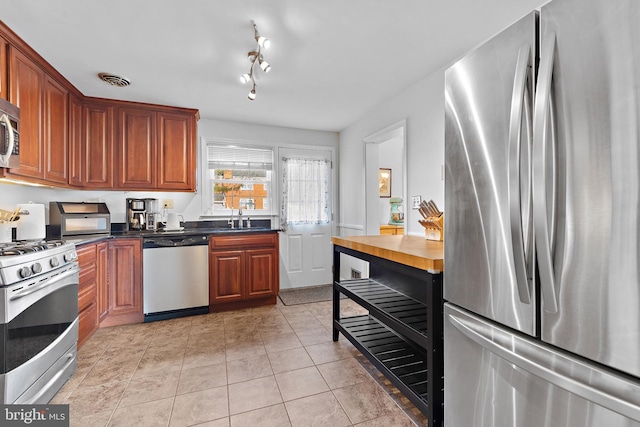 kitchen featuring appliances with stainless steel finishes, sink, and light tile patterned floors