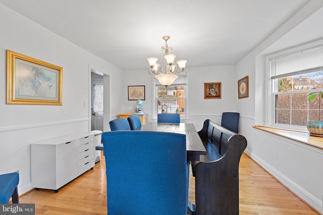 dining space with light hardwood / wood-style floors and a chandelier