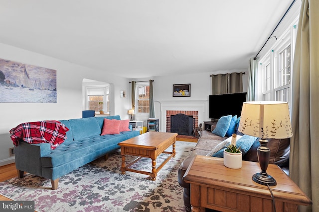 living room with a brick fireplace and light hardwood / wood-style flooring