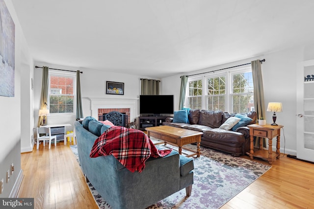 living room with a fireplace, a wealth of natural light, and light hardwood / wood-style flooring