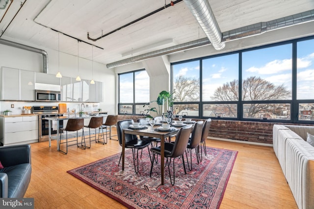 dining area with a towering ceiling and light hardwood / wood-style floors