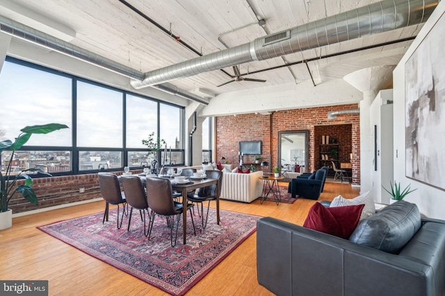 dining space featuring hardwood / wood-style flooring, brick wall, and ceiling fan