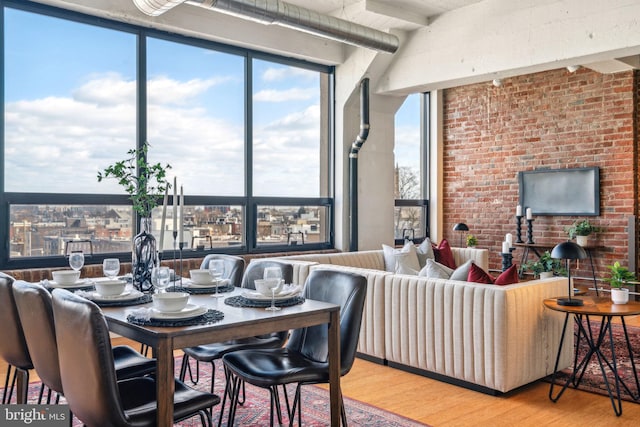 dining area featuring hardwood / wood-style flooring and brick wall