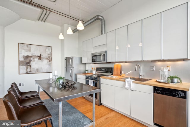 kitchen with hanging light fixtures, white cabinetry, appliances with stainless steel finishes, and sink