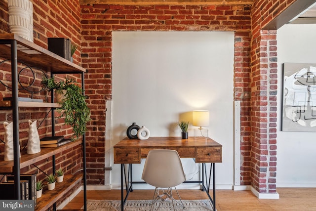 office space featuring hardwood / wood-style flooring and brick wall