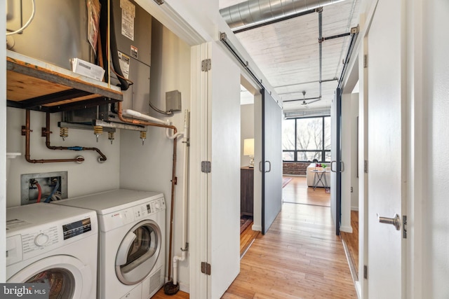 laundry area with water heater, light hardwood / wood-style floors, and washer and dryer