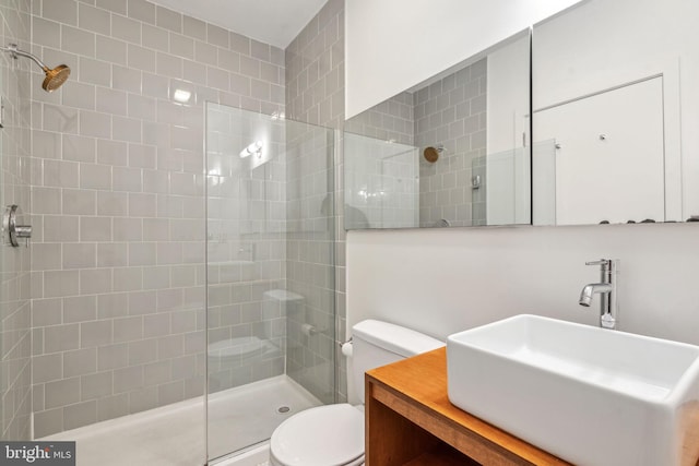 bathroom featuring tiled shower, vanity, and toilet