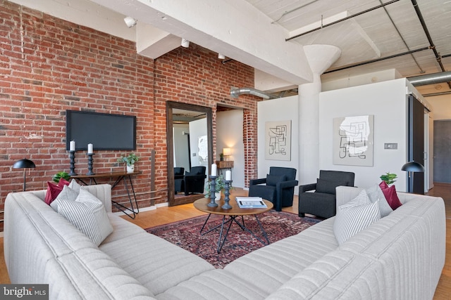 living room with hardwood / wood-style floors, a high ceiling, and brick wall