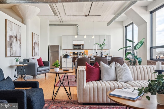 living room with a towering ceiling, wood-type flooring, and rail lighting