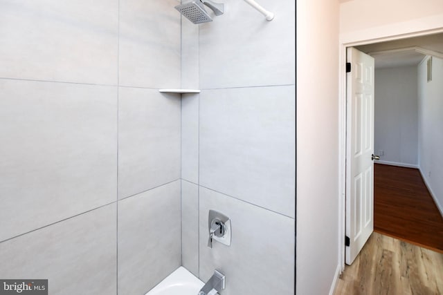 interior details with wood finished floors and tub / shower combination