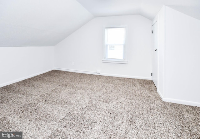 additional living space with baseboards, lofted ceiling, and carpet flooring