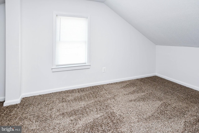 bonus room featuring lofted ceiling, carpet flooring, baseboards, and a textured ceiling