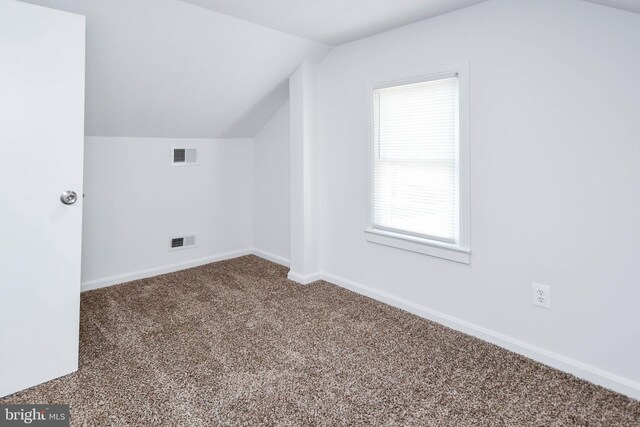 additional living space with vaulted ceiling, visible vents, baseboards, and carpet floors