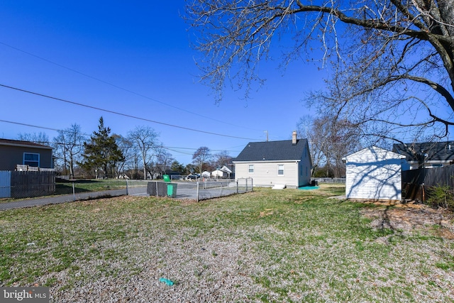 view of yard featuring a storage shed, fence, and an outbuilding