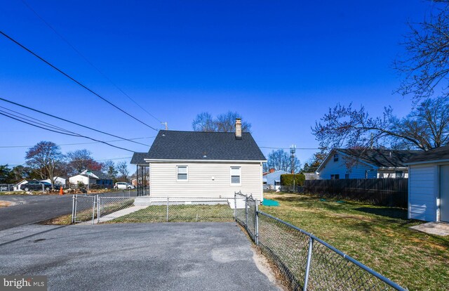 view of property exterior with a lawn, a gate, roof with shingles, fence private yard, and a chimney