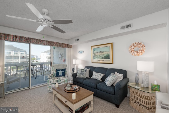 living room with a textured ceiling, visible vents, and a ceiling fan