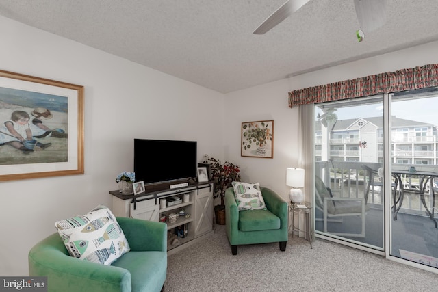 living area featuring carpet, ceiling fan, and a textured ceiling