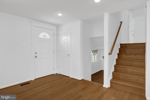 foyer entrance featuring visible vents, baseboards, stairway, recessed lighting, and wood finished floors