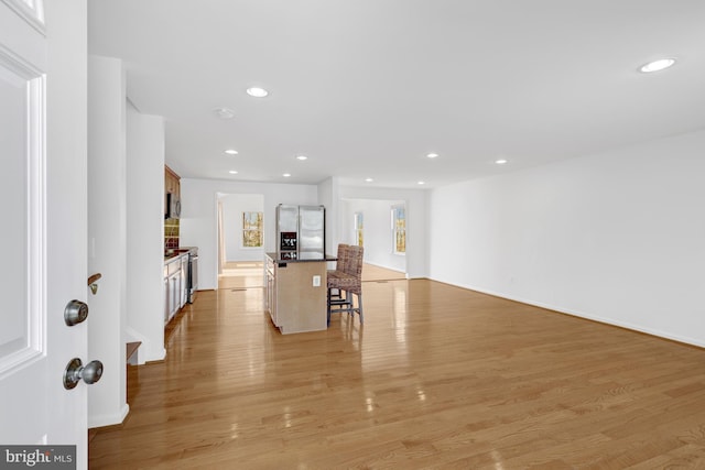 kitchen with light wood-type flooring, stainless steel appliances, a breakfast bar, and recessed lighting