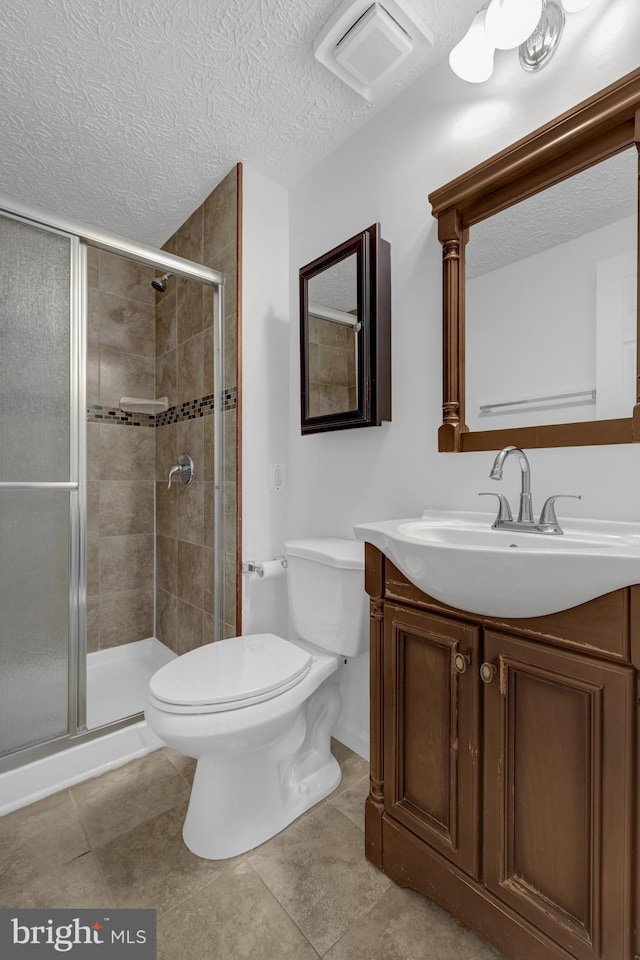 full bathroom featuring vanity, visible vents, a stall shower, a textured ceiling, and toilet