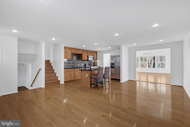 kitchen with dark countertops, a center island, wood finished floors, and stainless steel appliances