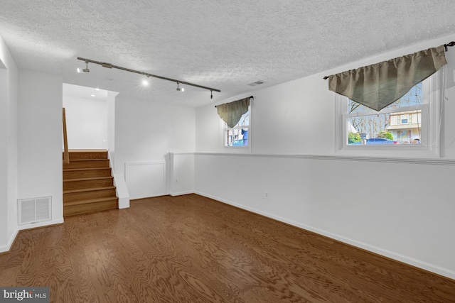 empty room with visible vents, baseboards, a textured ceiling, and stairs