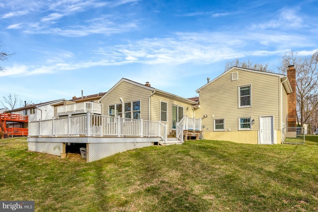 rear view of house featuring a wooden deck, a yard, and a chimney