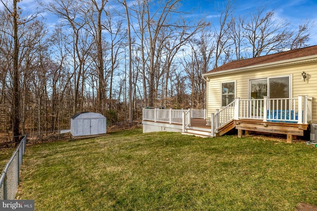 view of yard featuring an outbuilding, a fenced backyard, a storage shed, and a deck