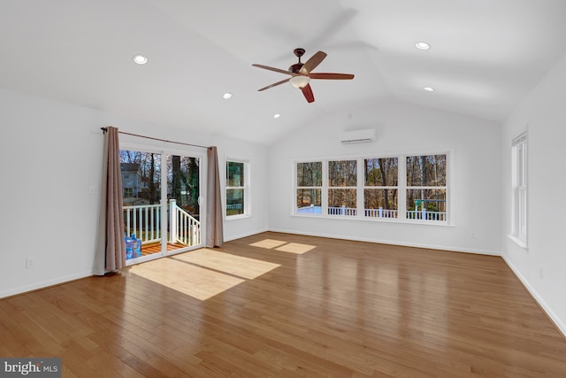 unfurnished living room featuring vaulted ceiling, plenty of natural light, a wall unit AC, and hardwood / wood-style flooring