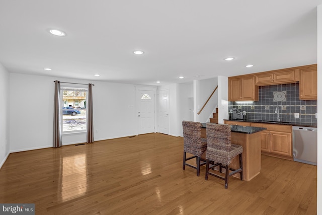 kitchen with a sink, light wood-style floors, dishwasher, and a breakfast bar area