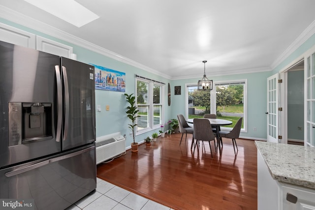 dining area with an AC wall unit, french doors, light wood-style flooring, crown molding, and a skylight
