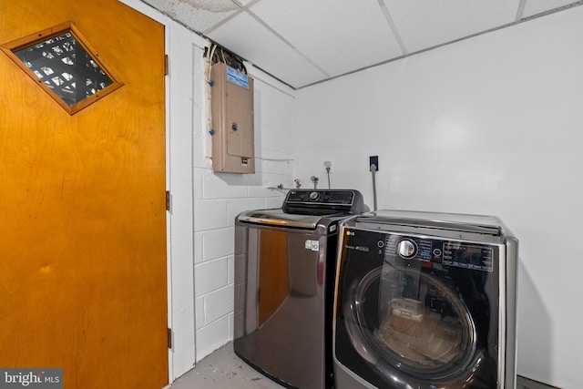 clothes washing area featuring electric panel, separate washer and dryer, laundry area, and concrete block wall