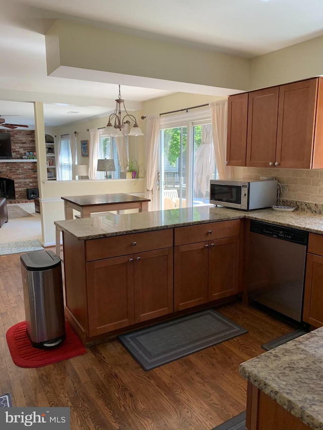 kitchen featuring appliances with stainless steel finishes, dark wood finished floors, a peninsula, and light stone counters