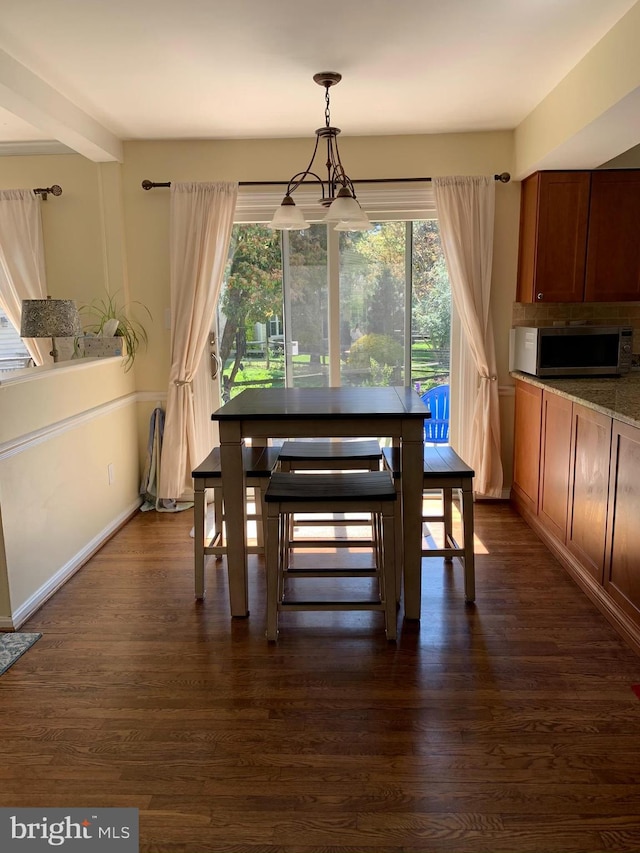 dining area with baseboards and dark wood-type flooring