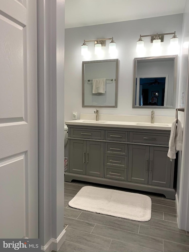 full bathroom featuring double vanity, wood finish floors, and baseboards