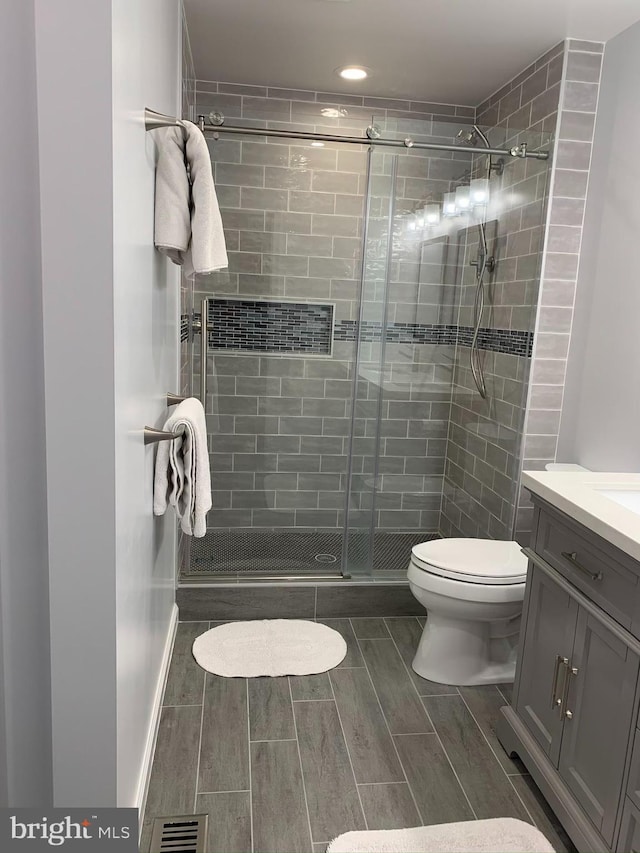 full bath with a shower stall, toilet, vanity, recessed lighting, and wood finish floors