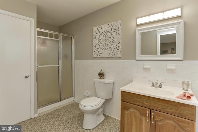 bathroom featuring vanity, toilet, tile walls, and a shower with shower door