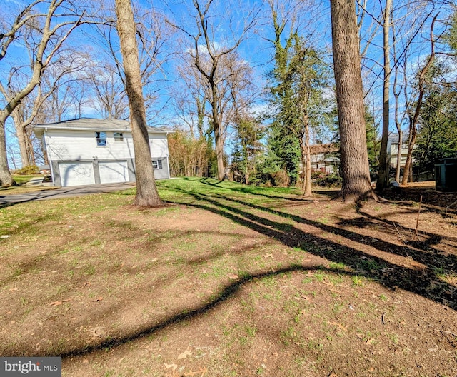 view of yard with aphalt driveway and an attached garage