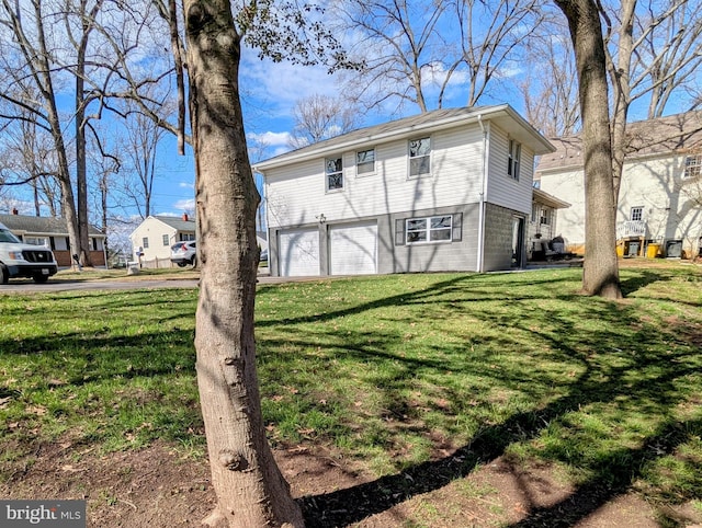 back of house featuring a lawn and an attached garage