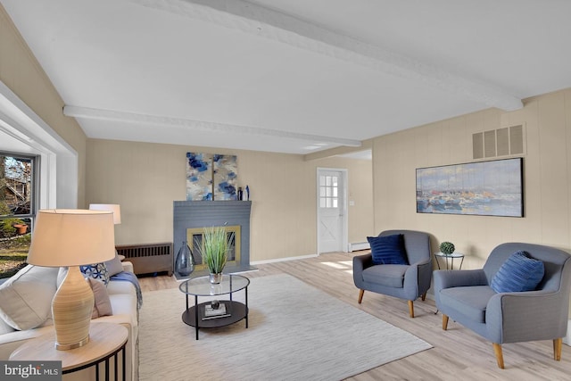 living room featuring a baseboard heating unit, light wood-type flooring, radiator heating unit, and beam ceiling