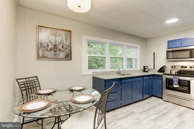 kitchen with blue cabinetry, sink, stainless steel appliances, light stone countertops, and light hardwood / wood-style floors