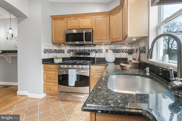 kitchen with stainless steel appliances, tasteful backsplash, visible vents, hanging light fixtures, and a sink